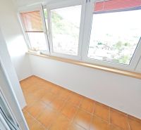Světlá lodžie se sklem a terakotovou dlažbou v 3-pokojovém bytě.