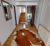 Interiér rodinného domu s podlahou s dřevěným dekorem a schodištěm se zábradlím.