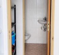 Koupelna v obchodních prostorách s toaletou a umyvadlem, jednoduchý dlaždičkový design.