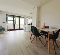 Světlý interiér 3pokojového bytu s bílými stěnami a podlahou s dřevěným dekorem.