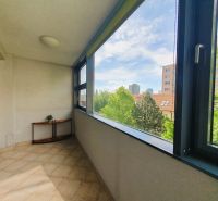 Zasklená lodžie v 3-pokojovém bytě s výhledem na zeleň a městskou panorámu.