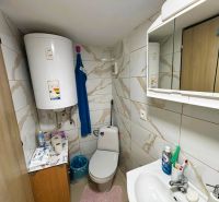 Koupelna s obklady a bojlerem nabízí základní hygienické potřeby a úložný prostor.