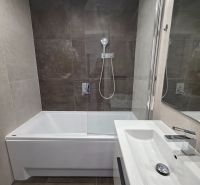 Koupelna v 3-pokojovém bytě s vanou, sprchovou zástěnou a moderním umyvadlem.