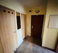 Chodba v 3-pokojovém bytě s dlažbou a dřevěnými dveřmi.