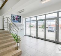 Interiér kanceláře se schodištěm, poštovními schránkami a velkými prosklenými dveřmi.