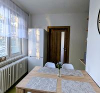 Jídelní kout v 2-pokojovém bytě s dřevěným stolem a bílými židlemi.