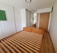 Ložnice v 2-pokojovém bytě s dřevěnou postelí, vestavěnou skříní a dekorací na stěně.