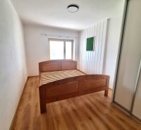 Ložnice s dřevěnou postelí a vestavěnou skříní v 2-pokojovém bytě.