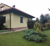 Rodinný dům v Trebostově s upravenou zahradou a dřevěnými detaily střechy.