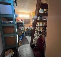 Úložný prostor s policemi a schodištěm v rodinném domě.