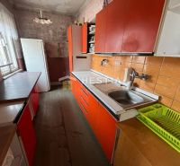 Kuchyně v rodinném domě s oranžovými skříňkami a podlahou s dřevěným dekorem.