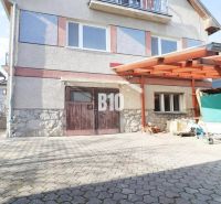 Rodinný dům v Turanech s dřevěným přístřeškem a příjezdovou cestou.