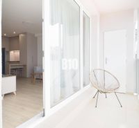 Balkon s výhledem do 1pokojového bytu, podlaha s dřevěným dekorem, příjemné posezení.
