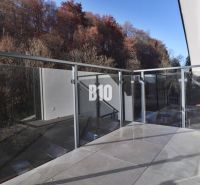 Balkon 2-pokojového bytu v Dolním Kubíně se skleněným zábradlím a okolím stromů.
