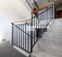 Schodiště s kovovým zábradlím v Rekreačním apartmánu, světlo proniká oknem.