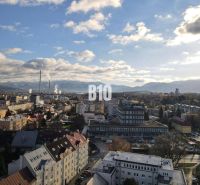 Město Žilina s panoramatem, bytové domy a průmyslová zóna v popředí.