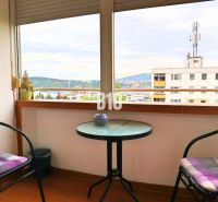 Balkon s výhledem na Žilinu ze 4pokojového bytu, dvě židle, stolek.