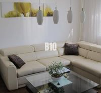 Elegantní obývací pokoj ve 4-pokojovém bytě s krémovou sedačkou a podlahou s dřevěným dekorem.