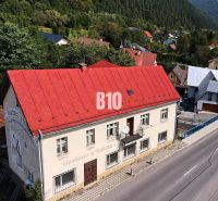 Budova v Belej s červenou střechou na hlavní ulici obklopená zelení a domy.