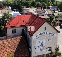 Hostinec v Bílé s červenou střechou a nástěnnou malbou muže s pivem.