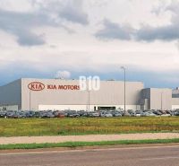Budova Kia Motors v Žilině, pozemky - komerční se zaparkovanými auty a travnatou plochou.