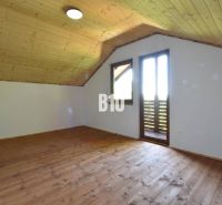 Podkrovní pokoj s dřevěným obložením a podlahou v Chatě u Bytče.
