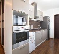 Kuchyně v 3-pokojovém bytě s podlahou s dřevěným dekorem a moderním vybavením.