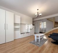 Obývací pokoj v rekreačním apartmánu s bílým nábytkem a podlahou s dřevěným dekorem.