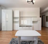 Interiér rekreačního apartmánu s bílým nábytkem a podlahou s dřevěným dekorem.