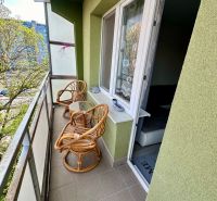 Balkon se dvěma ratanovými křesly a stolkem, výhled na zeleň, 3pokojový byt.