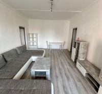 Obývací pokoj s podlahou s dřevěným dekorem a šedou sedací soupravou ve 3-pokojovém bytě.