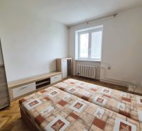 Pokoj v 3-pokojovém bytě s dvoulůžkem a podlahou s dřevěným dekorem.