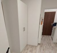 Útulná garsonka s bílým nábytkem a podlahou s dřevěným dekorem.