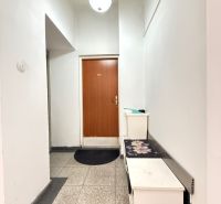 Chodba s bílými stěnami a hnědými dveřmi v 2-pokojovém bytě.