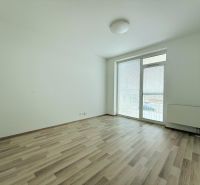 Pokoj v 2-pokojovém bytě s podlahou s dřevěným dekorem a vstupem na balkon.