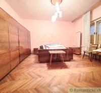 Ložnice v rodinném domě s podlahou s dřevěným dekorem, lustr, skříně, židle.