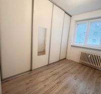 Pokoj ve 3-pokojovém bytě s bílou skříní a podlahou s dřevěným dekorem.