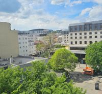 Pohled na Poštovní ulici v Bratislavě - Starém Městě se zelení a budovami.