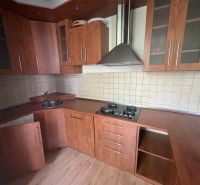 Kuchyně ve 2-pokojovém bytě s podlahou s dřevěným dekorem a hnědou linkou.