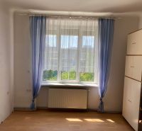Pokoj se skříňkou, oknem a závěsy v 2-pokojovém bytě, podlaha s dřevěným dekorem.