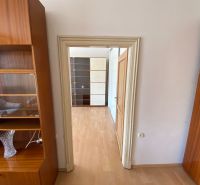 Interiér 2-pokojového bytu s podlahou s dřevěným dekorem a dřevěným nábytkem.