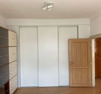 Interiér 2-pokojového bytu s bílou skříní a policovou sestavou, podlaha s dřevěným dekorem.