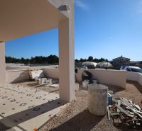 Stavební práce na terase rekreačního apartmánu ve Vodicích, slunečný den, viditelné nádoby a materiál.