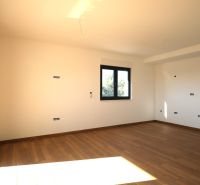 Prostorná místnost s velkým oknem a podlahou s dřevěným dekorem v Rekreačním apartmánu.