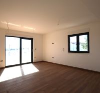 Interiér rekreačního apartmánu s velkými okny a podlahou s dřevěným dekorem.