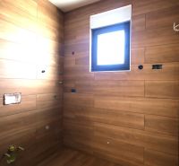 Rekreační apartmán s obklady v dřevěném dekoru a malým oknem.