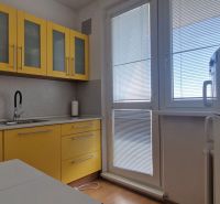 Kuchyně se žlutými skříňkami v 2pokojovém bytě, podlaha s dřevěným dekorem.