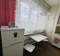 Kuchyně v 3-pokojovém bytě, s lednicí a stolem, záclony, červené kostkované závěsy.