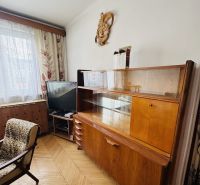 Pohled do obývacího pokoje s retro nábytkem a podlahou s dřevěným dekorem ve 3-pokojovém bytě.