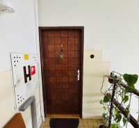 Vstupní dveře 3pokojového bytu s číslem devět, vedoucí na schodiště.